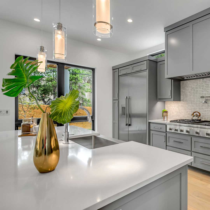 Industrial look kitchen with gray counter and three modern ceiling lamps